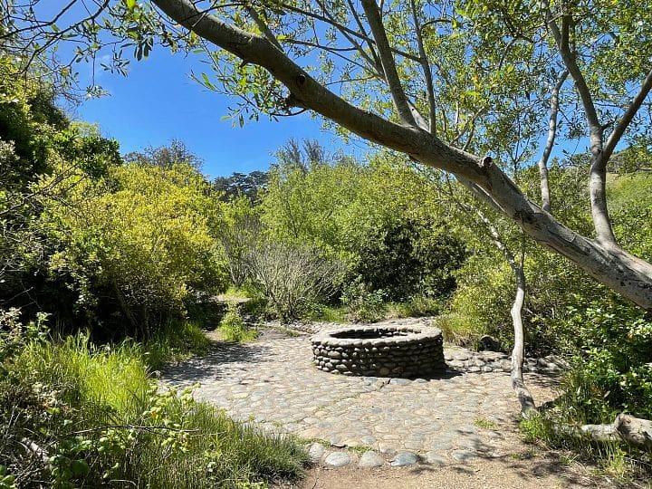 A photo of a restored stone spring surrounded by greenery.