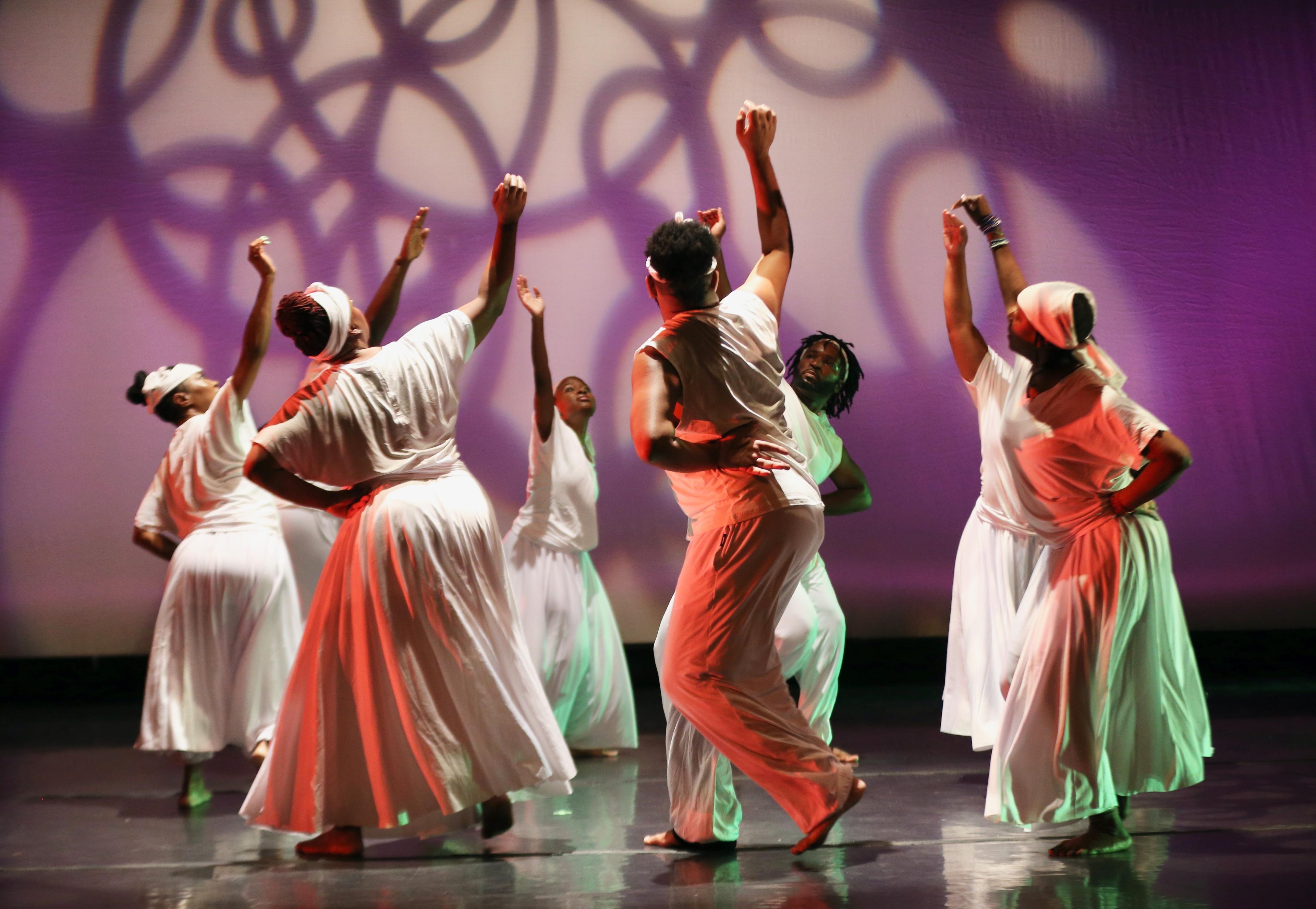 group of adults dancing on stage with shadows behind them