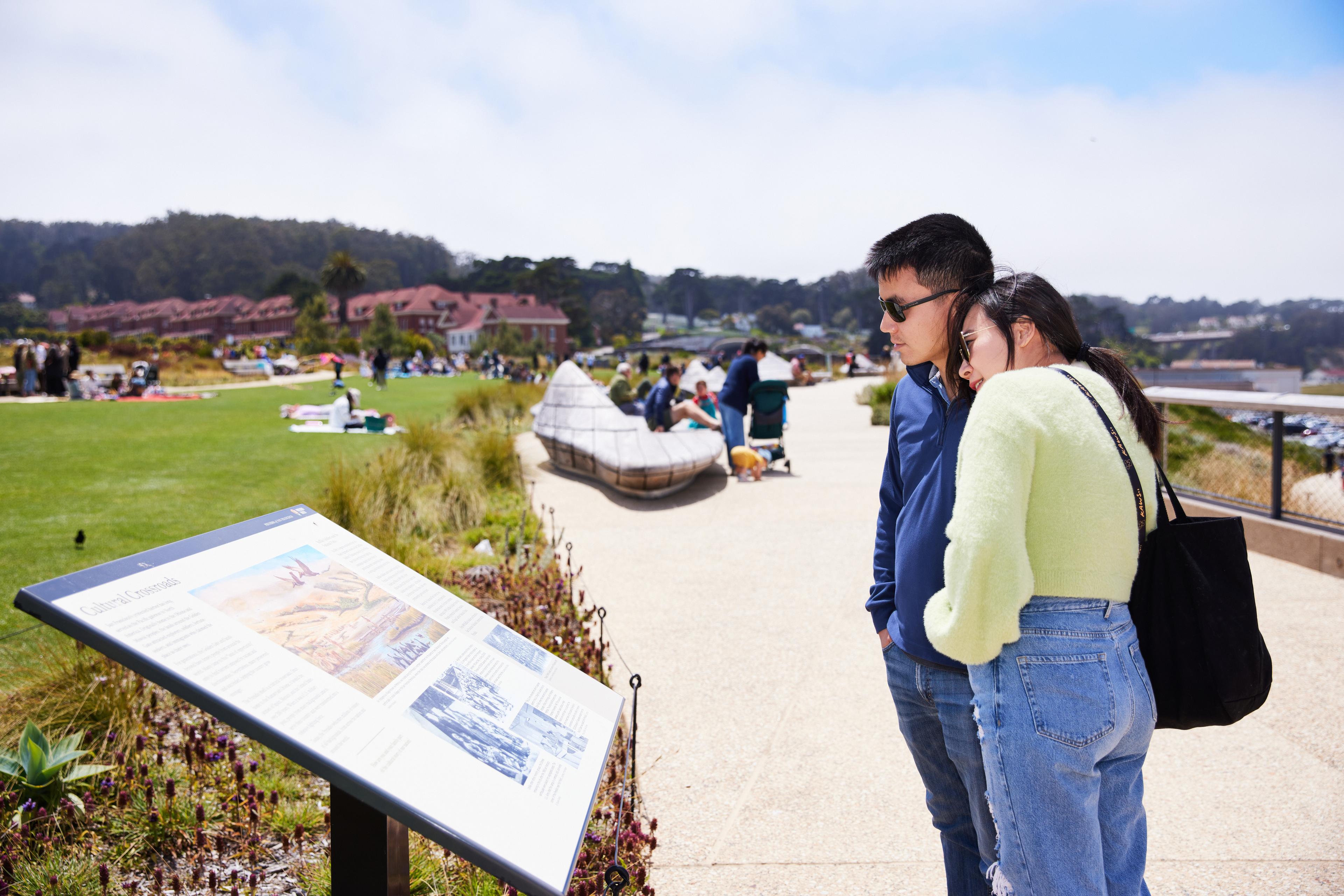 young couple leaning onto each other while reading a sign at the Presidio Tunnel Tops