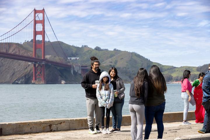 Family takes a photo with the Golden Gate Bridge at Torpedo Wharf.